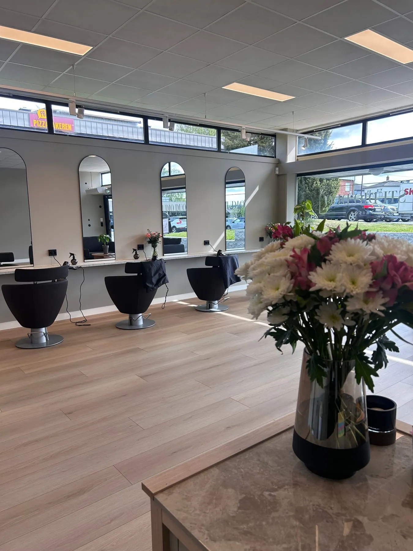 Salongen hos Studio Duo Frisør med buede speil, stylingstoler og store vinduer